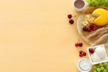 Top view photo of dairy products over pastel yellow background. Symbols of jewish holiday - Shavuot