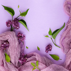 lilac flowers and leaves on a pink-lilac background with fabric drapery. flat lay, copy space.