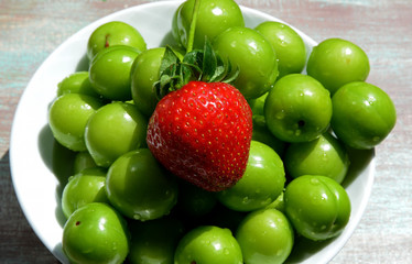 fresh plums and strawberries on wooden background