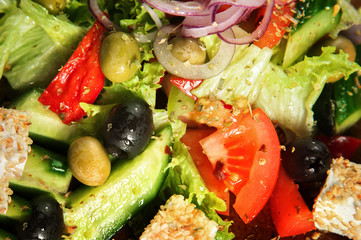 
Greek salad close-up. Healthy eating Olives, cheese, greens, lettuce, onions, tomatoes, appetizingly served on a brown plate