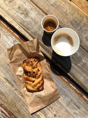 coffee cappuccino and espresso in eco friendly cardboard cups and sweet pastries for takeaway on a wooden background on the street. hard shadows and selective focus