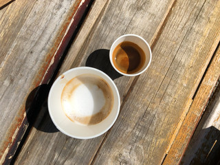 coffee cappuccino and espresso in eco friendly cardboard cups and sweet pastries for takeaway on a wooden background on the street. hard shadows and selective focus