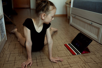 The girl is engaged in dancing at home. Self-isolation. Remote learning at home with a tablet.