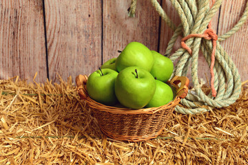 closeup green apples in basket on hay bale