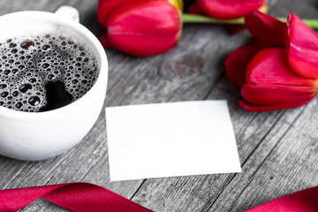 Fototapeta na wymiar Red tulips greeting card and coffee cup, wooden table. Top view with copyspace, place for inscription. Floral background for congratulations on Valentine's Day, Women's Day, Mother's Day or Birthday.