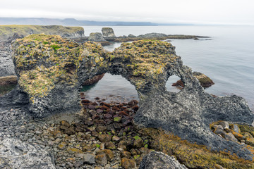 Natural volcanic rock arch in Arnarstapi in West Iceland. Basalt columns and textured rock seaside...