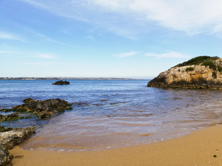 beautiful summer scenery. rocks on the sand. calm waves on the water. clouds on the sky. wide...