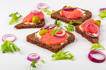 Appetizer, open sandwich with salmon and onion on white background. Traditional Italian or Scandinavian cuisine. Concept of proper nutrition and healthy eating. Close up, copy space for text