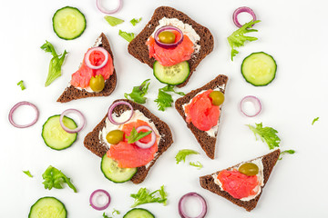 Appetizer, open sandwich with salmon, onion and cucumber on white background. Traditional Italian or Scandinavian cuisine. Concept of proper nutrition and healthy eating. Flat lay