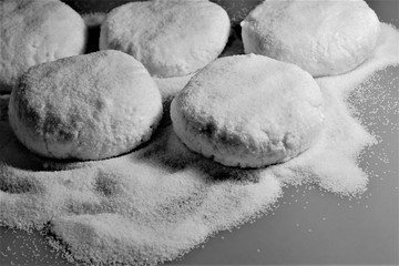 Composition in black and white: blanks of homemade cottage cheese pancakes before frying and sprinkled flour