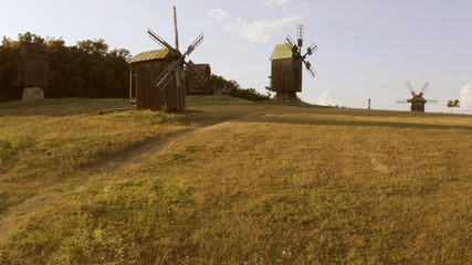 Obraz premium Old wooden windmills and big green meadow. Few little clouds on the rural sky.