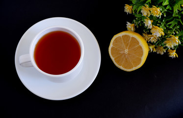 Herbal tea in a white mug and lemon on a black background. Suitable for advertising backgrounds and...