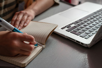 Young woman working at home, Student girl writing in note pad & looking at computer , online shopping, work or studying from home, freelance, online learning, distance education concept