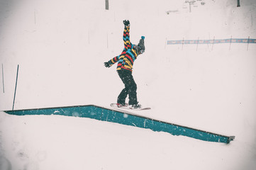 Freerider snowboarder doing basic snowboard rails trick in freestyle snowpark. Winter mountain season 