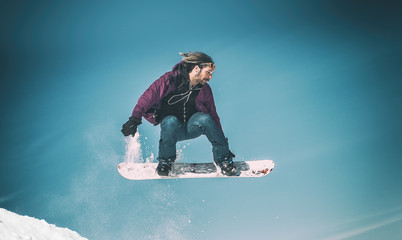 Freerider snowboarder doing speed trick air jump with his snowboard. Winter mountain freeride
