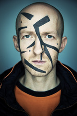 Close up portrait of man hiding his face from camera recognition with special camouflage makeup. Digital privacy in big city concept image.