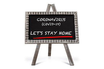 Chalkboard with word “CORONAVIRUS (COVID-19) LET’S STAY HOME” on wooden table with lots of natural light in background.