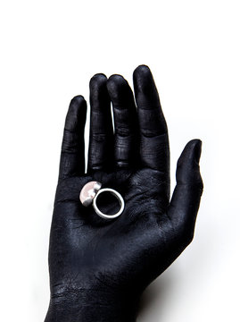 Black painted hand holding a silver ring