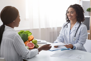 Female dietician giving patient informative brochure, clinic interior