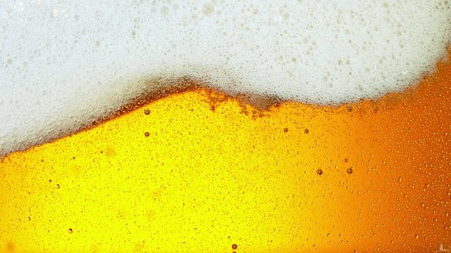 Super Slow Motion Detail Shot of Rippling Beer Bubbles and Foam in Glass at 1000fps.