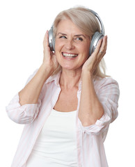 Beautiful senior blonde woman is listening to music in wireless headphones