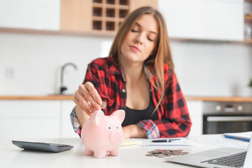 Woman putting money into piggy bank at table