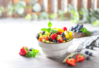 Fresh organic fruit salad on a light concrete background.