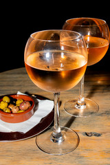 A glass of cold chilled rose wine served at a restaurant table. Water droplets are dripping
