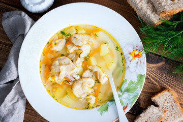Homemade chicken soup with dumplings in a white plate, selective focus