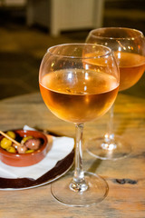 A glass of cold chilled rose wine served at a restaurant table. Water droplets are dripping
