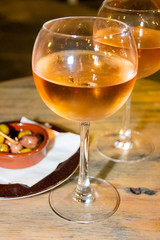 A glass of cold chilled rose wine served at a restaurant table. Water droplets are dripping