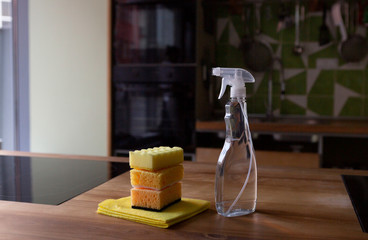 Spray detergent with spirit and pile of sponges on kitchen table