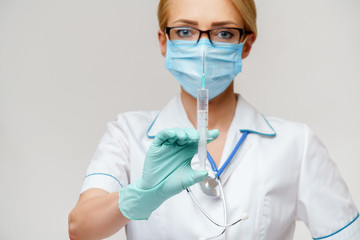 medical doctor nurse woman wearing protective mask and gloves - holding syringe