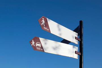 Metal signs indicating the direction against the blue sky.