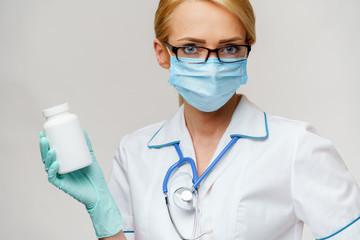 medical doctor nurse woman wearing protective mask and rubber or latex gloves - holding can of pills