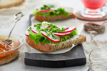 Sandwich with cottage cheese, radish, green onions and lettuce on a chopping Board. The concept of healthy Breakfast.