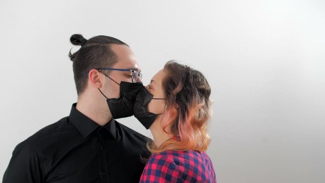 Portrait of modern husband and wife in protective medical black masks are hugging and kissing. Happy loving couple in quarantine due coronavirus or covid-19. Quarantined family stay at home 