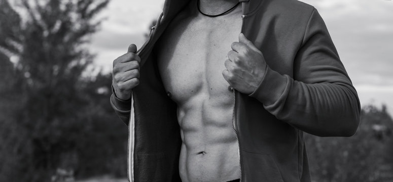 Black and white photo - close up of male muscular torso, during an outdoor sports training. Male power.