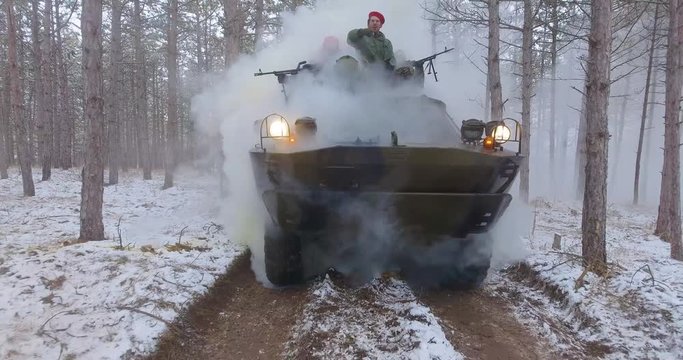 Winter. Smoke grenade. an APC with soldiers is approaching along a forest road