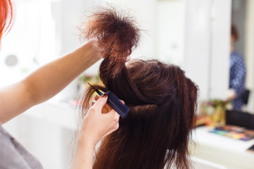 Naklejka premium Stylist align the customer's hair with straightener