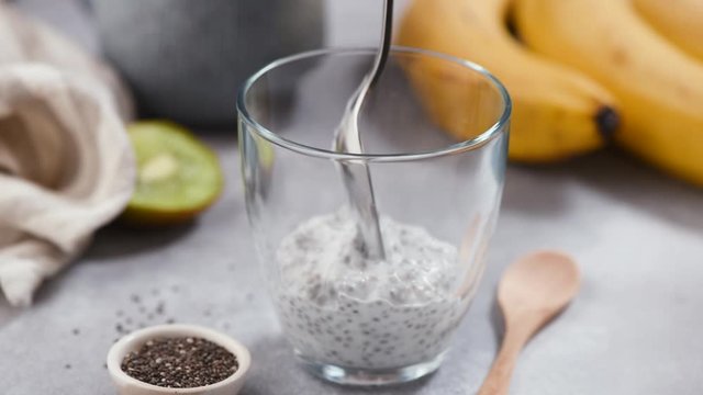 Chia seed pudding with fruits banana and kiwi. Time lapse preparing chia pudding in glass. Healthy vegan vegetarian food