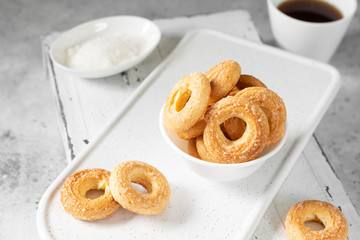 Puff pastry sprinkled with sugar in a white plate on a light gray background. Cookies sprinkled with sugar. Sweet pastries