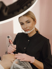 Permanent makeup teacher with her student girl. Very beautiful eyebrow master at her studio. Make...