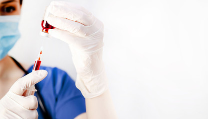 Girl doctor holds a syringe in her hand with a medicine against coronavirus on a white background with copy space for your text