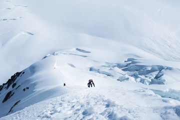 Group of climbers reach the summit of mountain peak  climbs a snowy ridge and enjoying the landscape view.