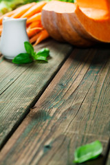 Healthy food cooking. Fresh garden carrots, onions, pumpkins, ginger and spices on rustic wooden background