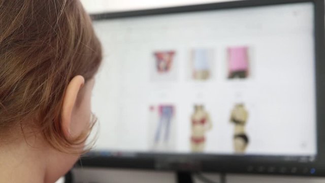 girl looks at the goods in the online clothing store. people use a computer, online shopping. Girl is choosing a lingerie . Close up.