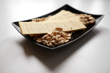 long potato chips, roasted peeled peanuts, salted beer snacks in black plate