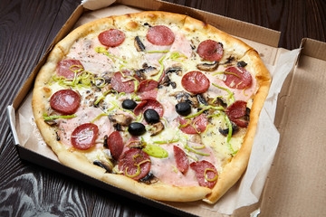 Pizza in a cardboard box on wooden table