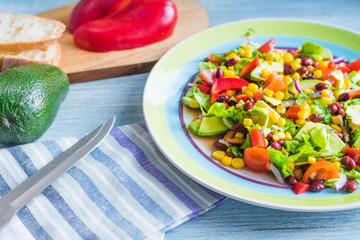 American-Mexican healthy salad with avocado, beans, corn, onions, lettuce and tomatoes in a plate